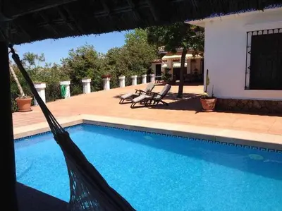a hammock in front of a house with a swimming pool at Espectacular casa con embarcadero. in Arcos de la Frontera