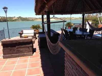 a patio with a hammock and a view of the water at Espectacular casa con embarcadero. in Arcos de la Frontera