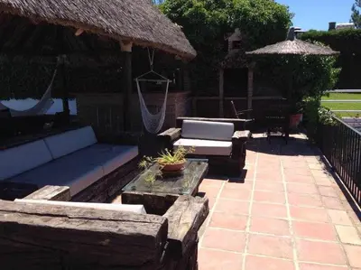 a patio with a couch and a table and an umbrella at Espectacular casa con embarcadero. in Arcos de la Frontera