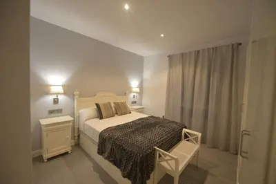 a bedroom with a bed and a chair and a window at Apartamento Victoria in Cádiz