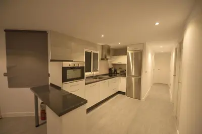 a kitchen with white cabinets and a black counter top at Apartamento Victoria in Cádiz