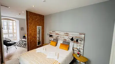 a bedroom with a bed with a wooden headboard at Apartamentos GADIR CENTRO in Cádiz