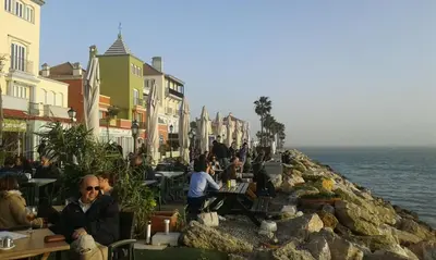 a group of people sitting at tables near the water at Apartamento Medina Puerto Sherry in El Puerto de Santa María