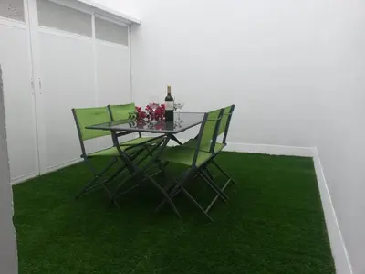 a table with green chairs and a bottle of wine at Apartamento Oropendola 9 in El Puerto de Santa María