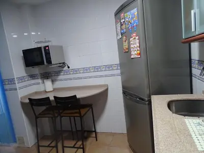 a kitchen with a refrigerator and a table and chairs at Apartamento Oropendola 9 in El Puerto de Santa María