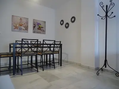 a room with a table and chairs and a wall with clocks at Apartamento Oropendola 9 in El Puerto de Santa María