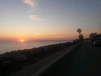 people walking down a road near the ocean at sunset at Apartamento Oropendola 9 in El Puerto de Santa María