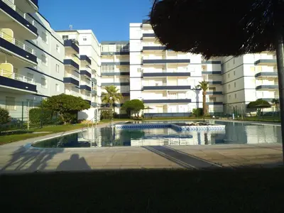 a swimming pool in front of a large building at Villablanca Apartamento in Chipiona