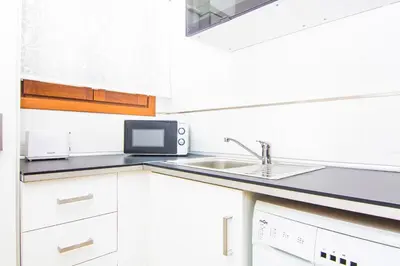 a white kitchen with a sink and a microwave at Apartamentos Centro Puerto de Santa Maria in El Puerto de Santa María