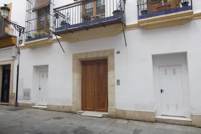 a white building with a wooden door and balconies at Apartamentos Centro Puerto de Santa Maria in El Puerto de Santa María