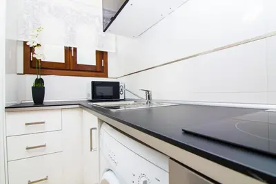 a kitchen with white cabinets and a black counter top at Apartamentos Centro Puerto de Santa Maria in El Puerto de Santa María