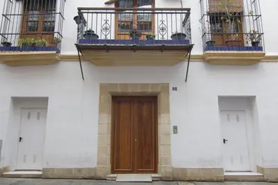 a white building with a wooden door and balconies at Apartamentos Centro Puerto de Santa Maria in El Puerto de Santa María