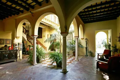 a lobby with columns and plants in a building at Posada de Palacio in Sanlúcar de Barrameda