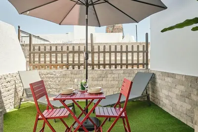 a table and chairs with an umbrella on a patio at Studio Novena Little Apartments in Cádiz