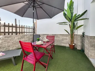 a red table and chairs with an umbrella on a patio at Studio Novena Little Apartments in Cádiz