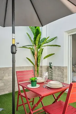 a red table with two red chairs and an umbrella at Studio Novena Little Apartments in Cádiz