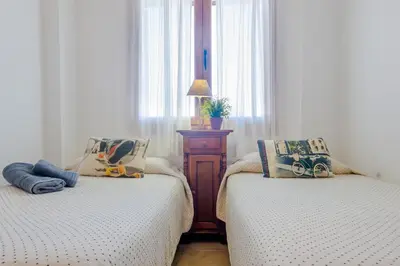 a bedroom with two beds and a table and window at Maracaibo in Chiclana de la Frontera