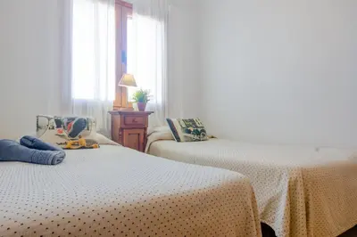 a bedroom with two beds and a table with a lamp at Maracaibo in Chiclana de la Frontera