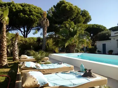 a pool with chaise lounges next to a resort at Kasbah Andaluz guest house in Chiclana de la Frontera