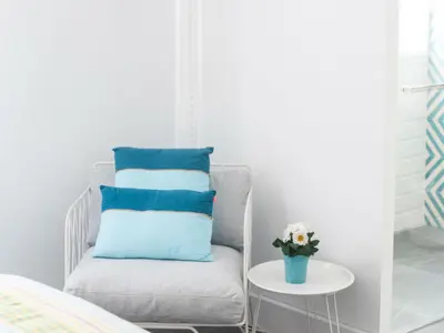 a white chair with blue pillows and a table at Hostal La Casa Sanlúcar in Sanlúcar de Barrameda