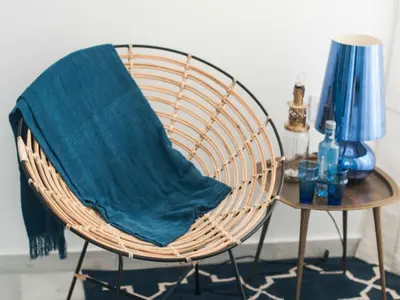 a wicker chair with a blue blanket on it next to a table at Hostal La Casa Sanlúcar in Sanlúcar de Barrameda