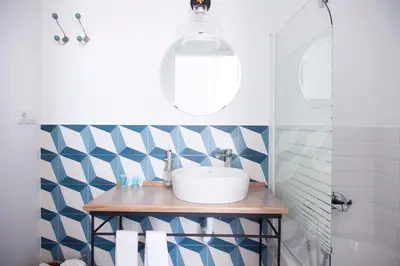 a bathroom with a sink and a blue and white patterned wall at Hostal La Casa Sanlúcar in Sanlúcar de Barrameda