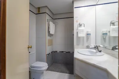 a bathroom with a toilet and a sink and a shower at Hotel Balneario de Chiclana in Chiclana de la Frontera