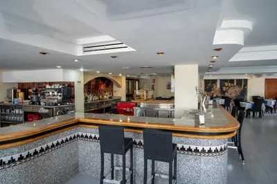 a bar in a restaurant with black chairs at Hotel Balneario de Chiclana in Chiclana de la Frontera