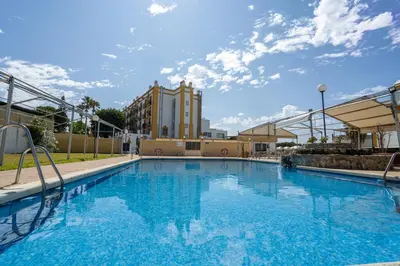 a large swimming pool with a building in the background at Hotel Balneario de Chiclana in Chiclana de la Frontera