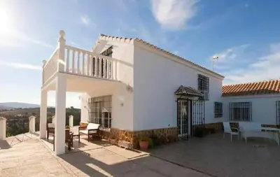 a white house with a balcony and a patio at Elegant Villa in Algar with Private Pool in Algar