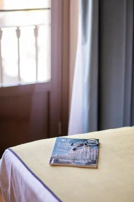 a magazine sitting on top of a bed with a window at Itaca Jerez by Soho Boutique in Jerez de la Frontera