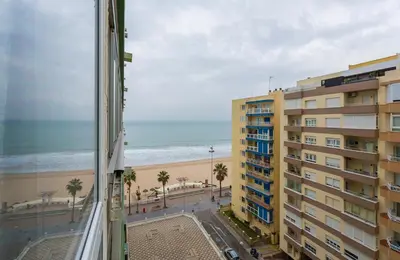 a view of the beach from a balcony of a building at Playa Victoria Paseo Marítimo 3 Rooms in Cádiz