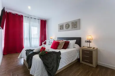 a bedroom with a large bed with red curtains at Playa Victoria Paseo Marítimo 3 Rooms in Cádiz