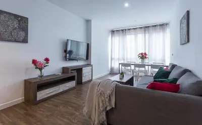 a living room with a couch and a tv and a table at Playa Victoria Paseo Marítimo 3 Rooms in Cádiz