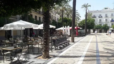 an empty street with tables and chairs and umbrellas at Sherryflat Azahar in Jerez de la Frontera