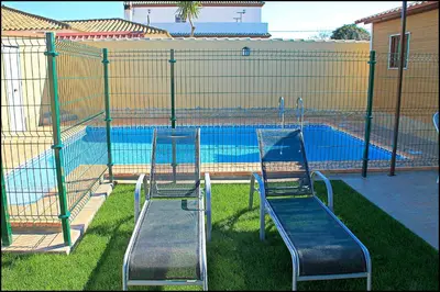 two chairs sitting in front of a swimming pool at Bungalow Curro Pareja 131 in Conil de la Frontera