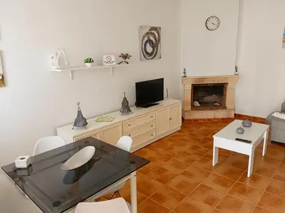 a living room with a table and a tv and a fireplace at Chalet Mari Carmen in Chiclana de la Frontera