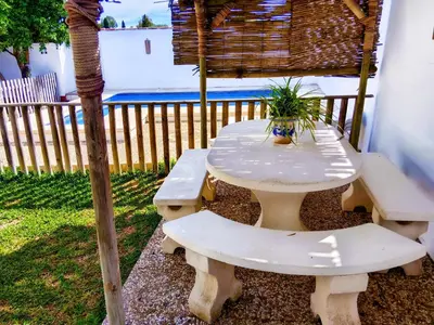 a white picnic table with two benches and a plant on it at Chalet Mari Carmen in Chiclana de la Frontera