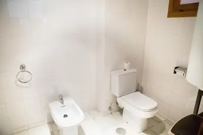 a white bathroom with a toilet and a sink at Apartamentos Turísticos Bahía Sur in San Fernando