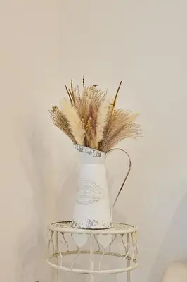 a white vase with some dried grass in it at Little Arboli Little Apartments in Cádiz