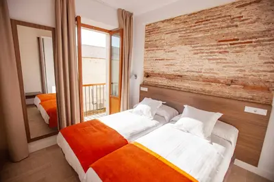 a bedroom with two beds and a brick wall at Apartamentos Maier in Cádiz