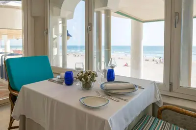 a table with a white table cloth and a view of the beach at Hotel Playa Victoria in Cádiz