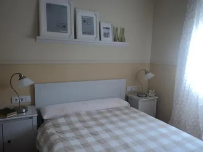 a bedroom with a bed with a checkered blanket and two lights at Apartamento Zona Norte in Jerez de la Frontera