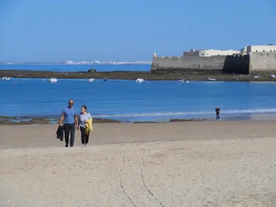a couple of people walking on the beach at La Nube de San Miguel in Cádiz
