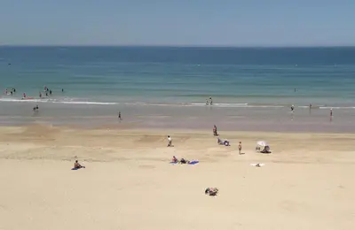 a group of people on a beach with the ocean at La Nube de San Miguel in Cádiz