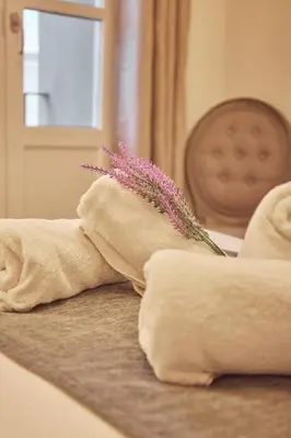 a pile of towels on a bed with a flower at Little Sopranis Little Apartments in Cádiz