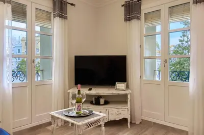 a living room with a tv and a table and windows at Little Sopranis Little Apartments in Cádiz