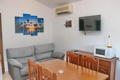 a living room with a couch and a table at Bungalow La Roa I in Conil de la Frontera