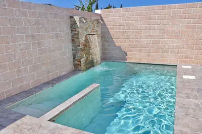 a swimming pool next to a brick wall at Bungalow La Roa I in Conil de la Frontera
