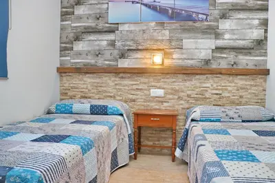 two beds in a room with a tv on a brick wall at Bungalow La Roa I in Conil de la Frontera